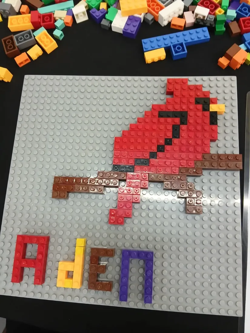 A red cardinal mosaic built from bricks, signed Aden